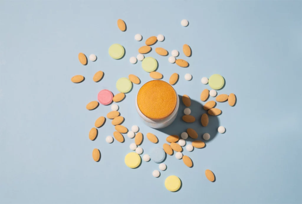 Assorted film coated tablets and pills in various colours and shapes on a light blue background.
